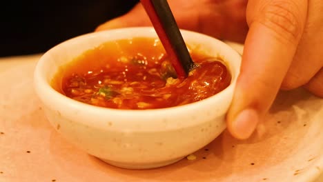 hand stirring sauce in a small bowl