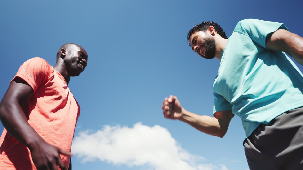 Two Men High-Fiving and Fist Bumping Under a Blue Sky