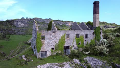 abandoned overgrown ivy covered desolate countryside historical welsh coastal brick factory mill aerial view front to left orbit