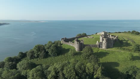 An-aerial-view-of-the-of-Llansteffan-Castle-in-Carmarthenshire,-South-Wales,-on-a-sunny-morning-with-a-clear-blue-sky