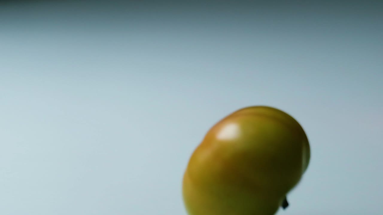 los tomates rojos y verdes caen en una superficie blanca en la vista del estudio
