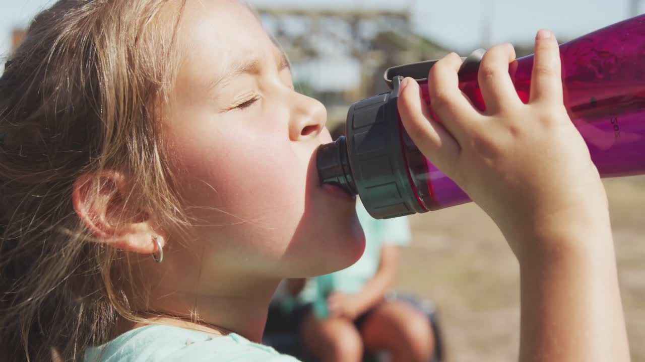 chica caucásica bebiendo agua en el campamento de entrenamiento