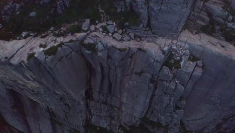 cliffside path with hikers walking along rugged terrain in norway’s mountainous landscape