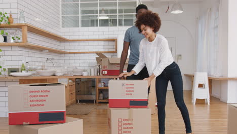 smiling young couple carrying boxes into new home on moving day