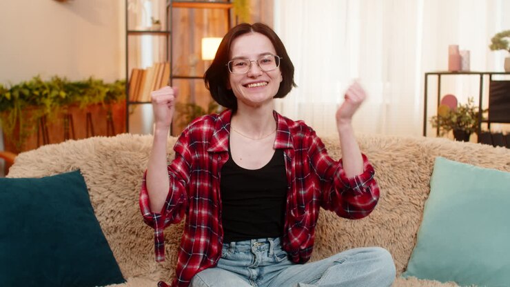 Donna che guarda la telecamera con un sorriso a casa che celebra la gioiosa vittoria con una fiducia positiva