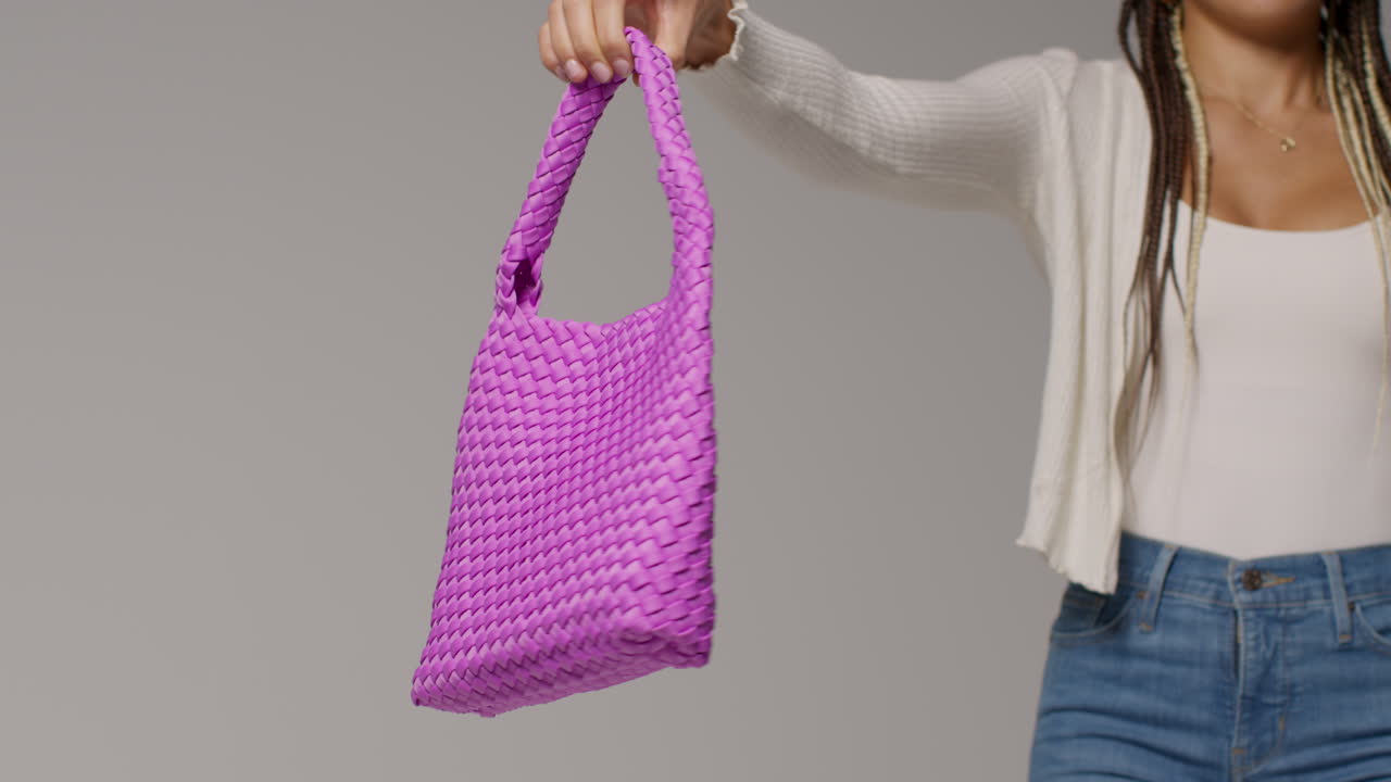 여성 소셜 미디어 인플루언서가 유저 생성 콘텐츠를 제작하고 보라색 패션 가방 1을 들고 있는 클로즈업