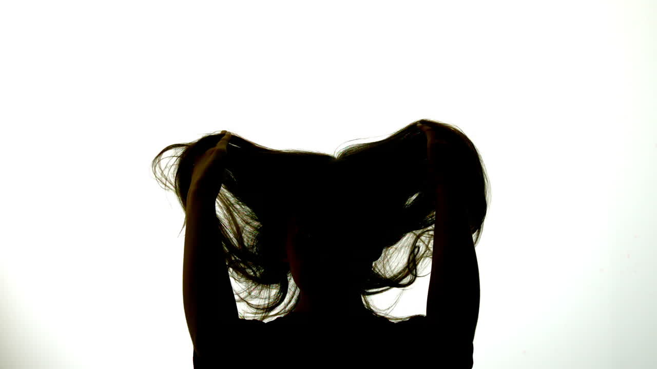 머리카락을 펴고 있는 매력적인 여성의 실루