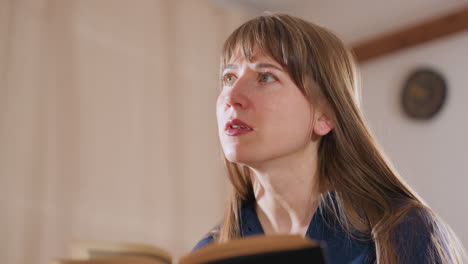 behavioral specialist with long hair reads observations from notebook while engaging in thoughtful conversation with client in softly lit room during therapy or coaching session