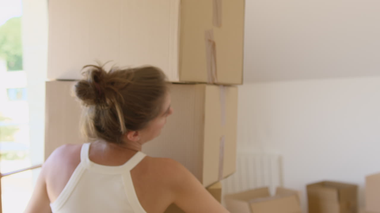 Attractive brunette carrying pile of boxes into new apartment