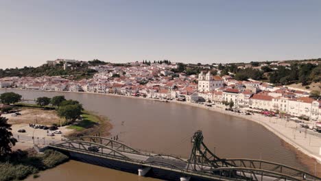 lifting bridge over river sado with majestic skyline view of alcacer do sal town, aerial