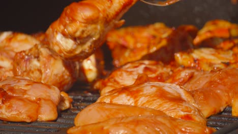 lots of marinated spicy sauce chicken on bbq grill with chef turning over different pieces including thighs and drumsticks. summer concept street food picnic footage