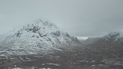 Drohnenaufnahme-Aus-Der-Luft-Von-Der-Isle-Of-Skye-Oder-Three-Sisters-An-Einem-Verschneiten-Wintertag-Mit-Dichten-Grauen-Wolken-Am-Himmel-In-Schottland,-Europa---Panoramablick-Von-Oben