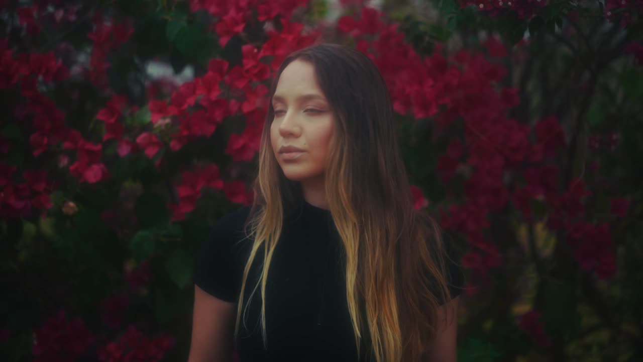 Jovem Mulher Pensativa Diante de Flores Vermelhas Vibrantes