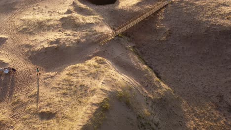 Isolierte-Person,-Die-Bei-Sonnenuntergang-Entlang-Einer-Hölzernen-Fußgängerbrücke-Am-Strand-Spaziert,-Punta-Del-Este-In-Uruguay