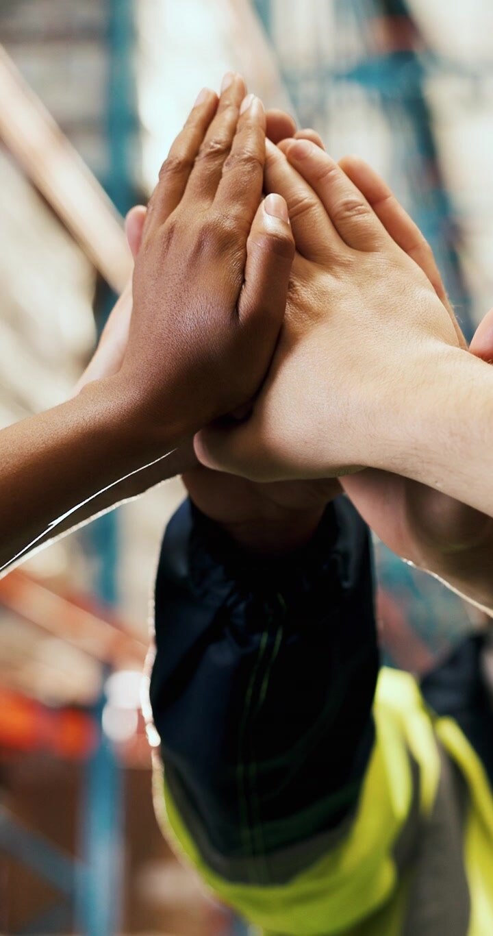 Diverse Warehouse Workers Joining Hands in Teamwork