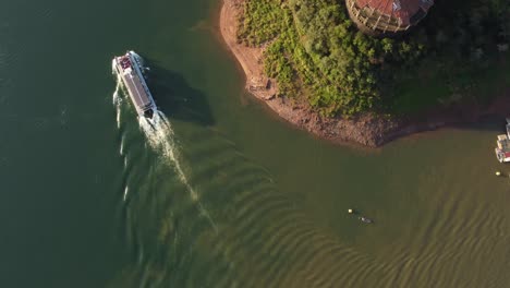 un dron disparó hacia abajo un transbordador turístico que navegaba por el río iguazú al atardecer - gente que visitaba la selva tropical natural en américa del sur