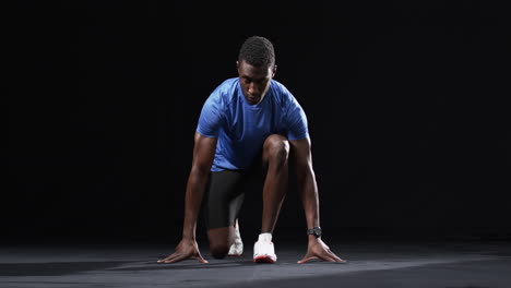 african american man in starting position for a sprint on a black background