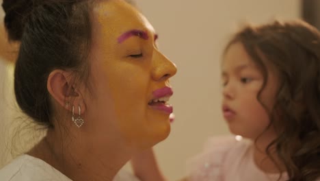 niña pequeña aplicando maquillaje a su madre embarazada en casa