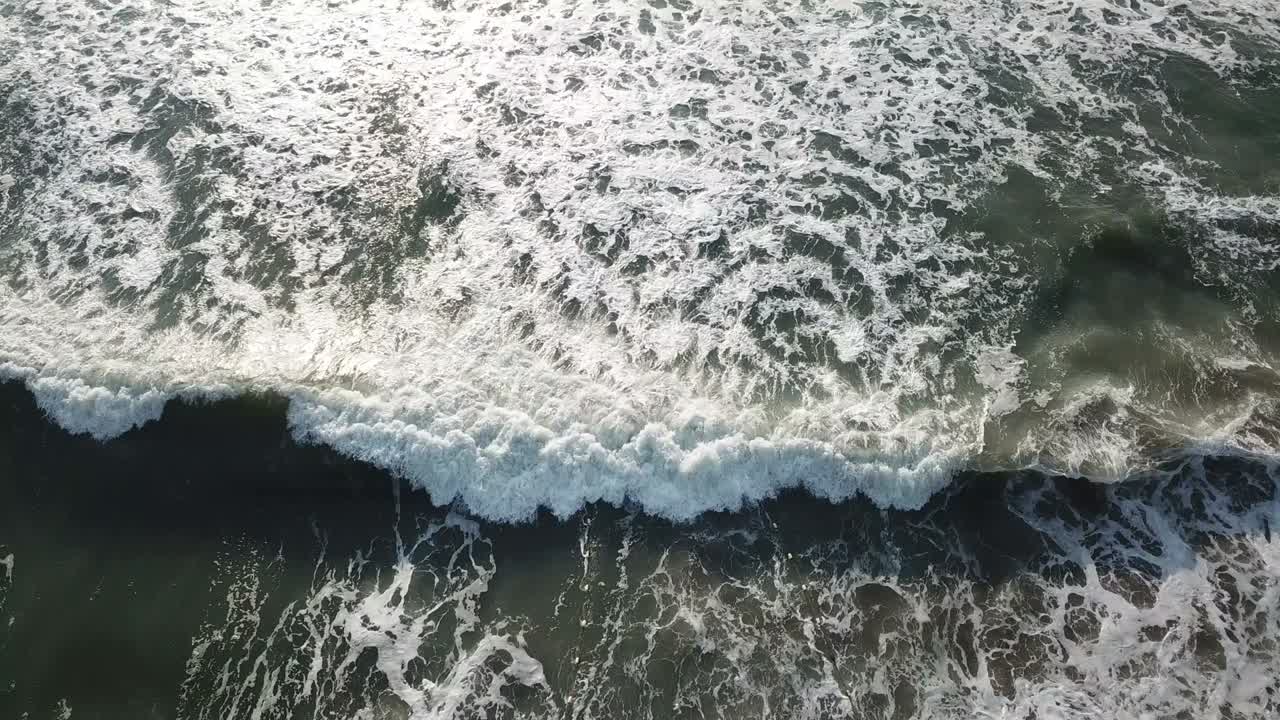 Aerial birds eye view looking down at sea waves crashing down. Green and blue sea top view drone, drone footage , 4k