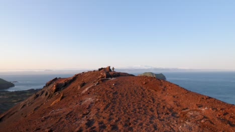 un excursionista anciano en la cresta volcánica roja con vistas panorámicas del océano en islandia