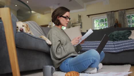 Mujer-Caucásica-Usando-Una-Computadora-Portátil-Trabajando-Desde-Casa-Con-Su-Perro-Mascota-En-El-Sofá-Junto-A-Ella