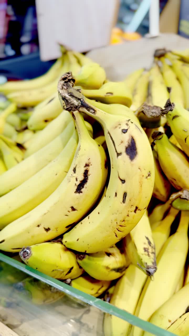 Hand holding a bunch of bananas in a grocery store