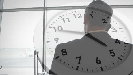 animation of clock with fast hands over caucasian businessman at airport talking on smartphone