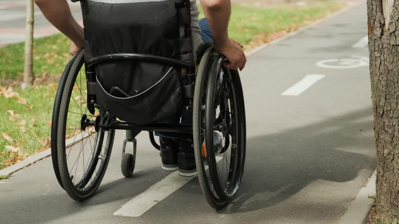 Man with disabilities in wheelchair walk at the park alley