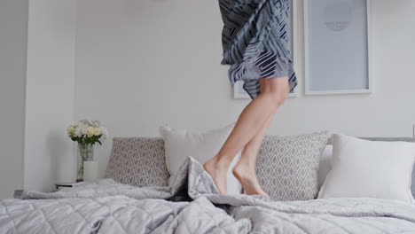 happy woman jumping on bed in hotel room having fun enjoying vacation lifestyle celebrating freedom