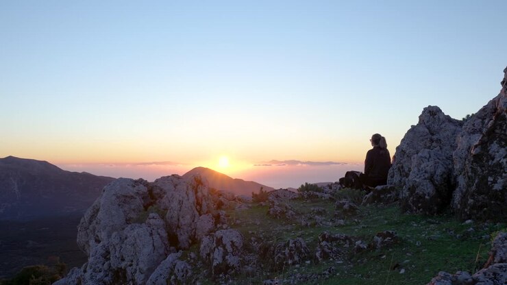 Vista del tramonto dalla cima di una montagna con una persona