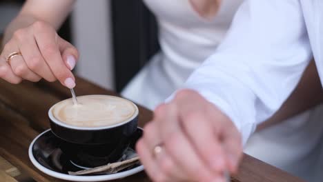 beautiful Brides in White Clothes Stir Coffee while Sitting at a Table in a Cafe Beautiful Brides in White Clothes Stir Coffee while Sitting at a Table in a Cafe Brides Walk in Sunny Weather