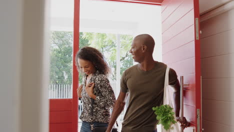 couple returning home from shopping trip carrying groceries in plastic free bags