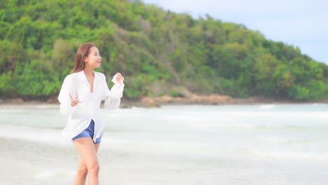 Cheerful-Asian-woman-barefoot-walking-on-tropical-summer-beach