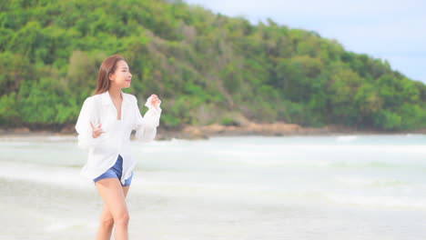 열 대 여름 해변에서 맨발로 걷는 쾌활 한 아시아 여자