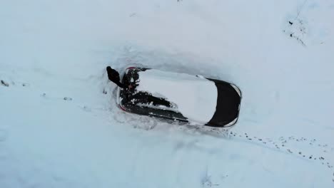 Hombre-Quitando-Una-Capa-De-Nieve-Pesada-Del-Techo-De-Los-Autos-En-La-Temporada-De-Invierno,-Vista-Aérea-De-Arriba-Hacia-Abajo