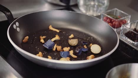 close up : adding mushrooms and vegetables to frying pan