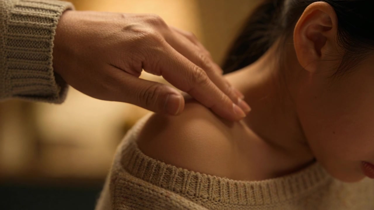 Entering hand from left stroking Asian woman cream-sweater right-shoulder for comfort at home lamp
