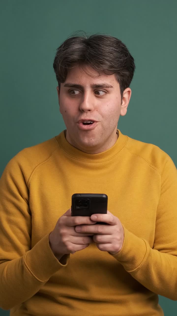 Successful man shouting joyfully with phone in green studio