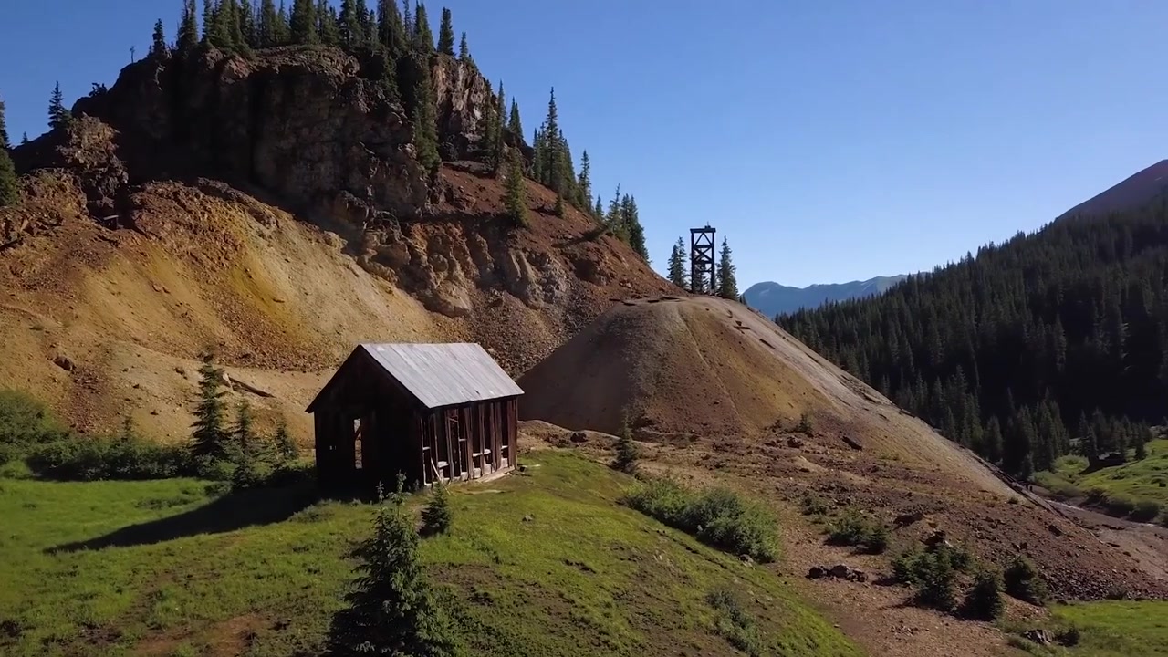 Rustik flygvy över ett gammalt gruvlägerhus i Colorado, som framhäver natursköna berg, historisk charm och filmiska lantliga texturer, perfekt för köpare av stock footage.