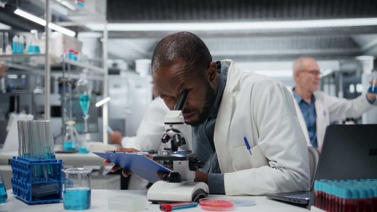Male cytotechnologist using optical microscope to study microorganisms
