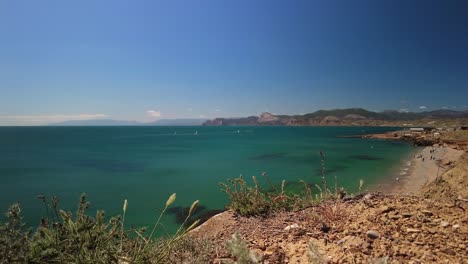 Crimea,-Cape-Megan,-surfers-with-a-sail-cut-through-the-green-water-of-the-Black-Sea-in-spring