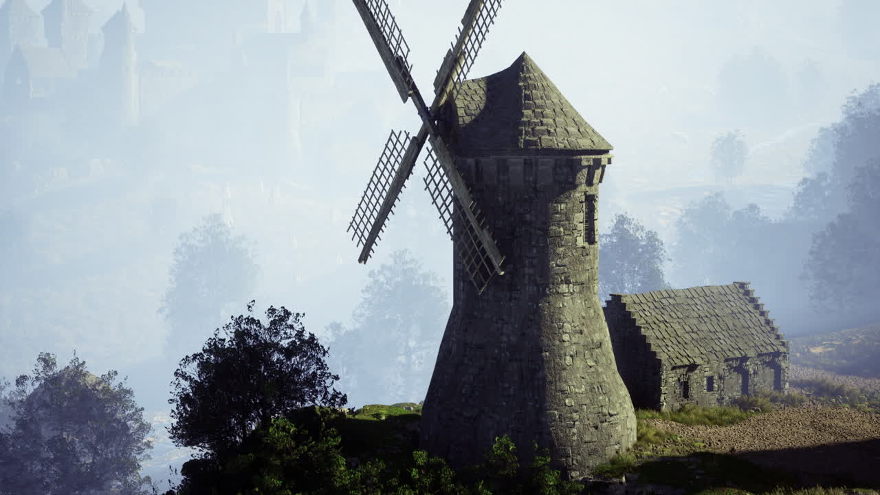 Historic windmill stands majestically on a hillside during early morning fog
