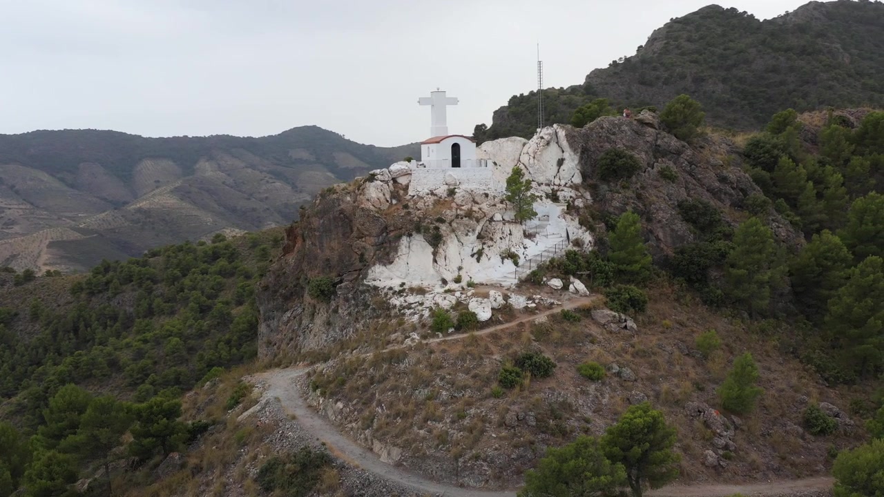 Turisté na vrcholu hory s malým bílým kostelíkem, Granada, Španělsko. Rotující stoupající dron.