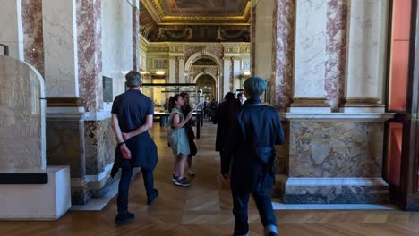 people walking through louvre's sculpture gallery