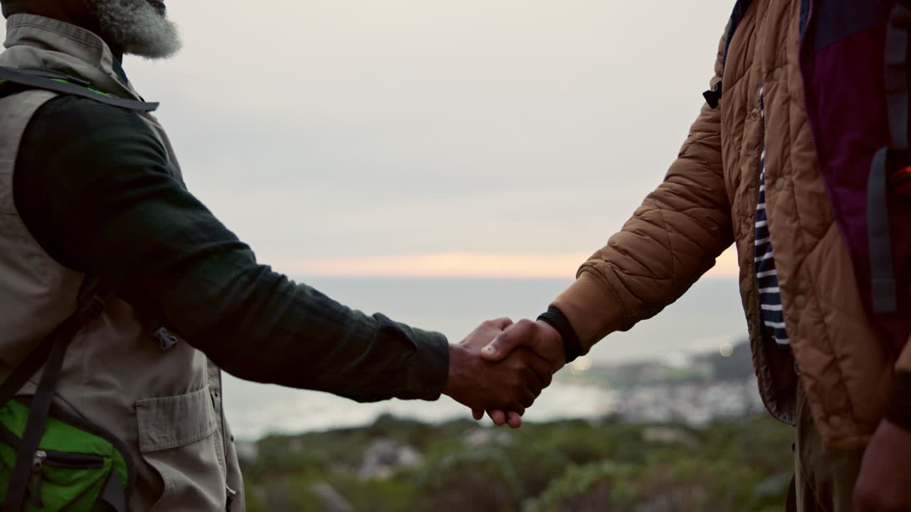Two hikers shaking hands on a mountain
