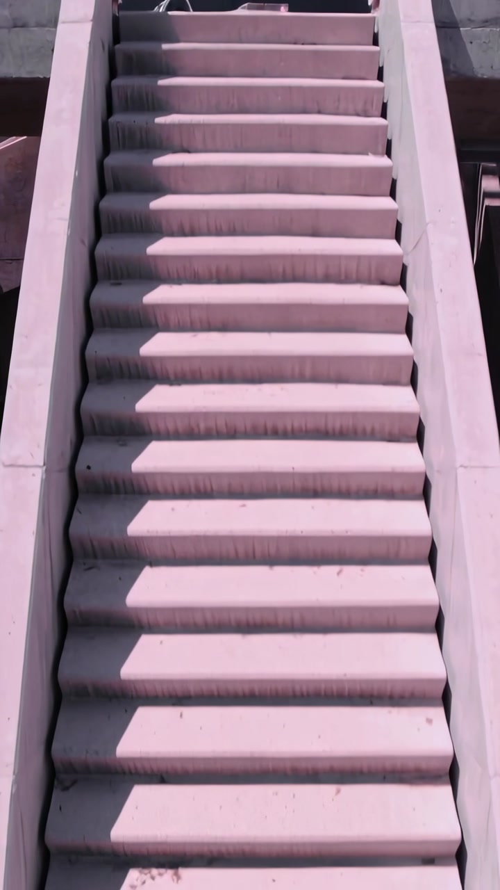Vertical video: Panning camera showing concrete stairs at top revealing shadows, ladder white cone