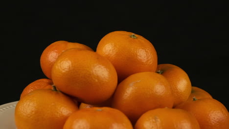 plate of clementine oranges rotates isolated on black background