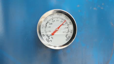 broken used a circular temperature gauge thermometer for measuring hot and steam temperature mounted on blue metal. industrial concept