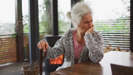 Senior-mixed-race-woman-leaning-on-walking-cane-and-thinking