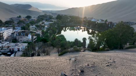 oasis del desierto huacachina, perú con lago y palmeras, con grandes dunas de arena en el fondo